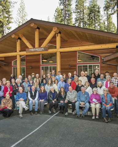 Large group of shareholders and guests gathered outside The Redwoods lodge building