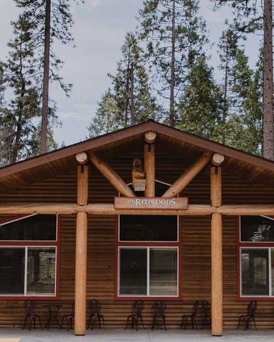 The Redwoods event center building exterior with log columns and pine forest backdrop