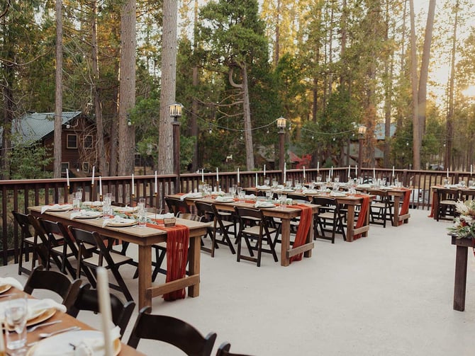 Outdoor reception at The Redwoods with farm tables, candles, and string lights under the pines